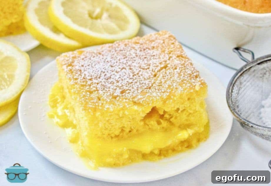 Slice of Easy Lemon Lava Cake on a white plate, garnished with powdered sugar, showcasing the two distinct layers