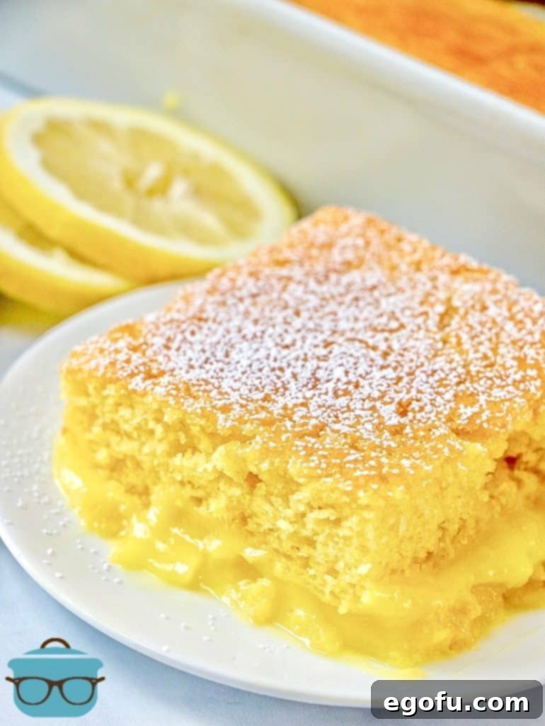 Warm Lemon Pudding Cake on a white plate with sliced lemons and powdered sugar