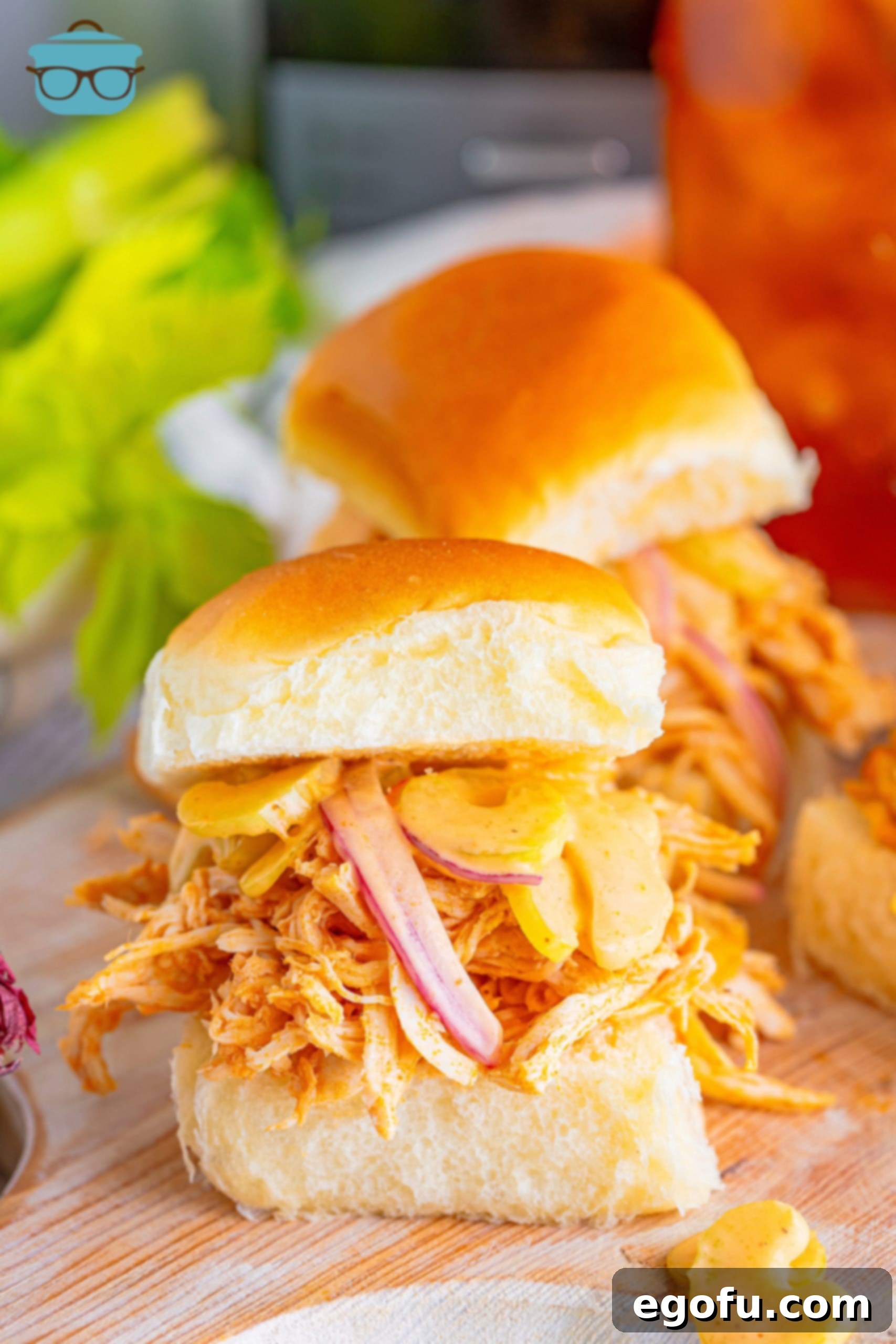 A vibrant close-up of several Crock Pot Buffalo Chicken Sliders, showcasing the shredded buffalo chicken on soft buns with the creamy ranch celery slaw on top, ready to be enjoyed.