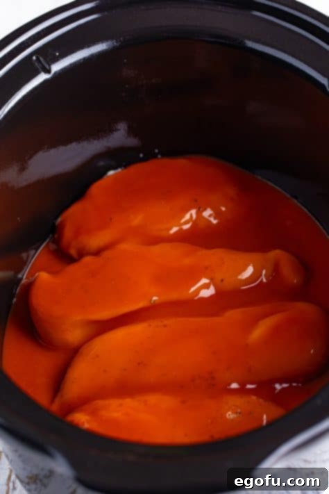 Buffalo sauce covered chicken breast in a crock pot.