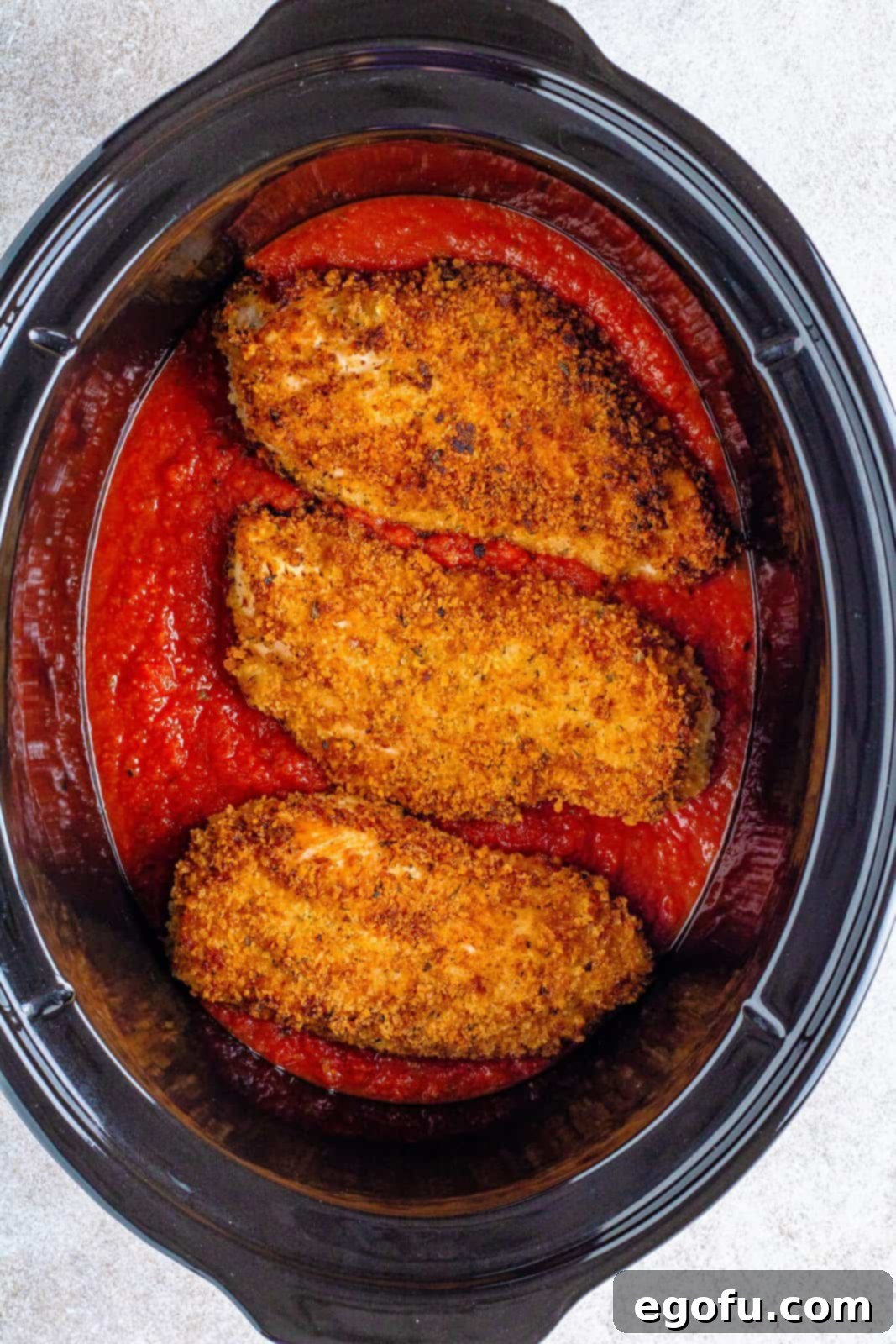 Slow Cooker Chicken Parm Perfection 12 Browned chicken breasts nestled in rich marinara sauce within an oval slow cooker.