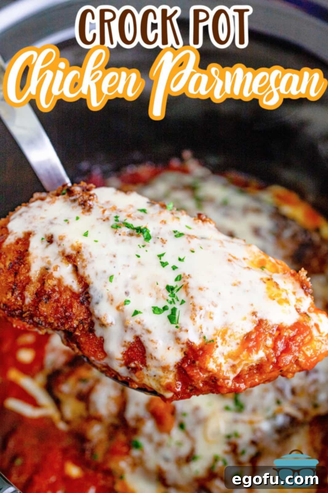 Slow Cooker Chicken Parm Perfection 4 A spatula lifting a perfectly cooked, cheese-covered chicken parmesan breast from the slow cooker, ready to be served.
