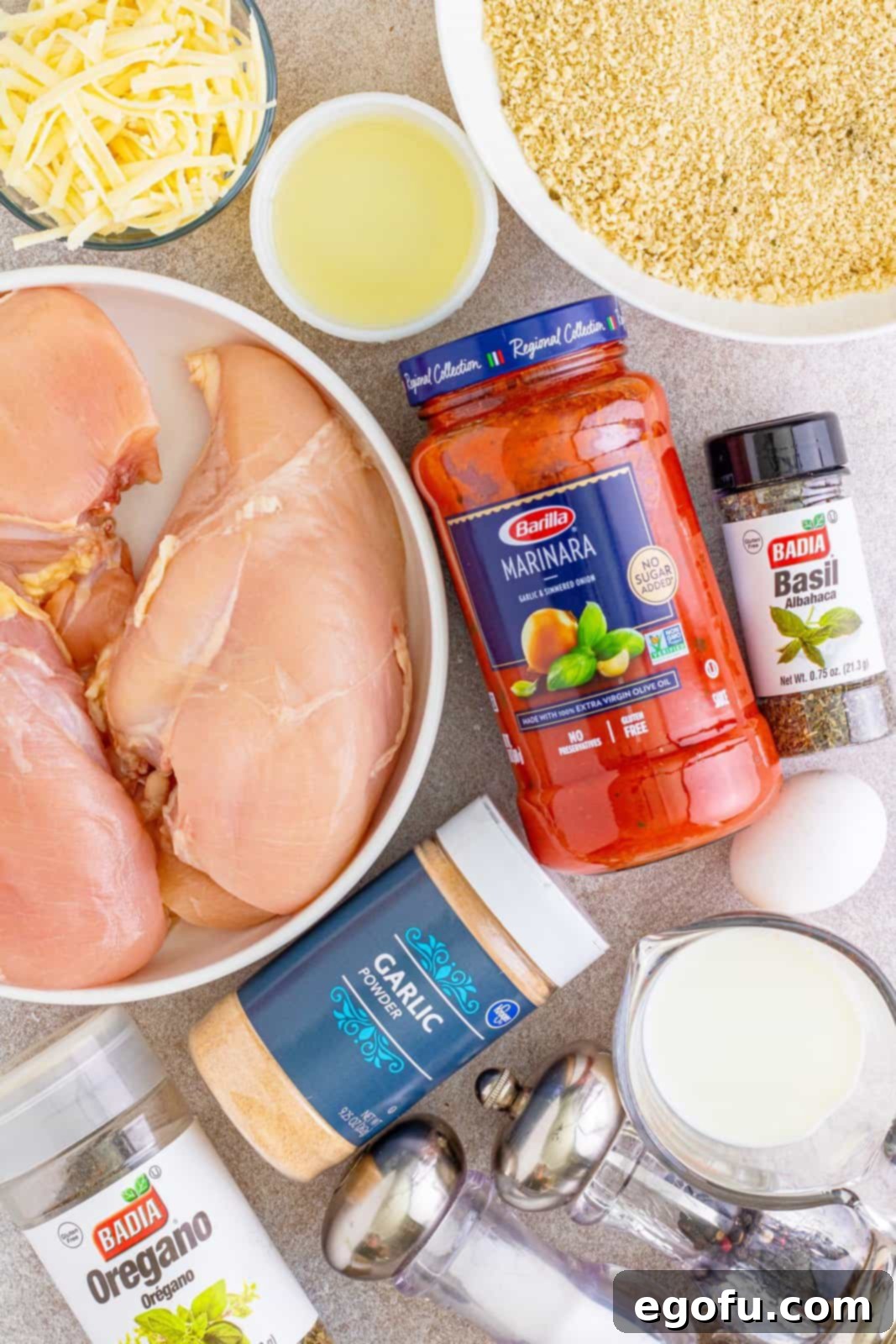 Slow Cooker Chicken Parm Perfection 5 All the ingredients for slow cooker chicken parmesan laid out: marinara sauce, fresh chicken breasts, panko bread crumbs, egg, milk, garlic powder, dried oregano, dried basil, shredded mozzarella cheese, and shredded Parmesan cheese.