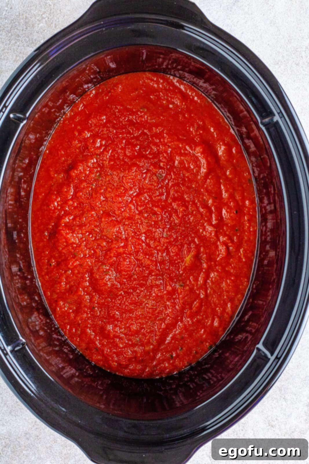 Slow Cooker Chicken Parm Perfection 6 Rich marinara sauce coating the bottom of a slow cooker, ready for the chicken.