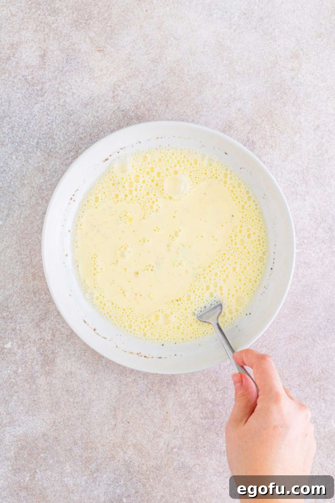 Slow Cooker Chicken Parm Perfection 7 A shallow bowl containing whisked egg, milk, salt, and pepper.