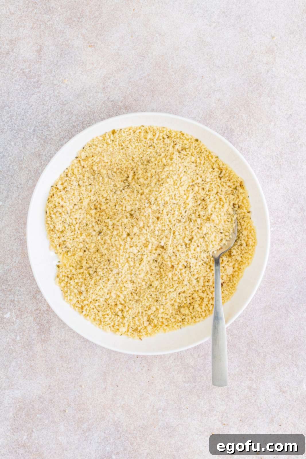 Slow Cooker Chicken Parm Perfection 8 Panko bread crumbs mixed with dried basil and oregano in a shallow white bowl, ready for coating.