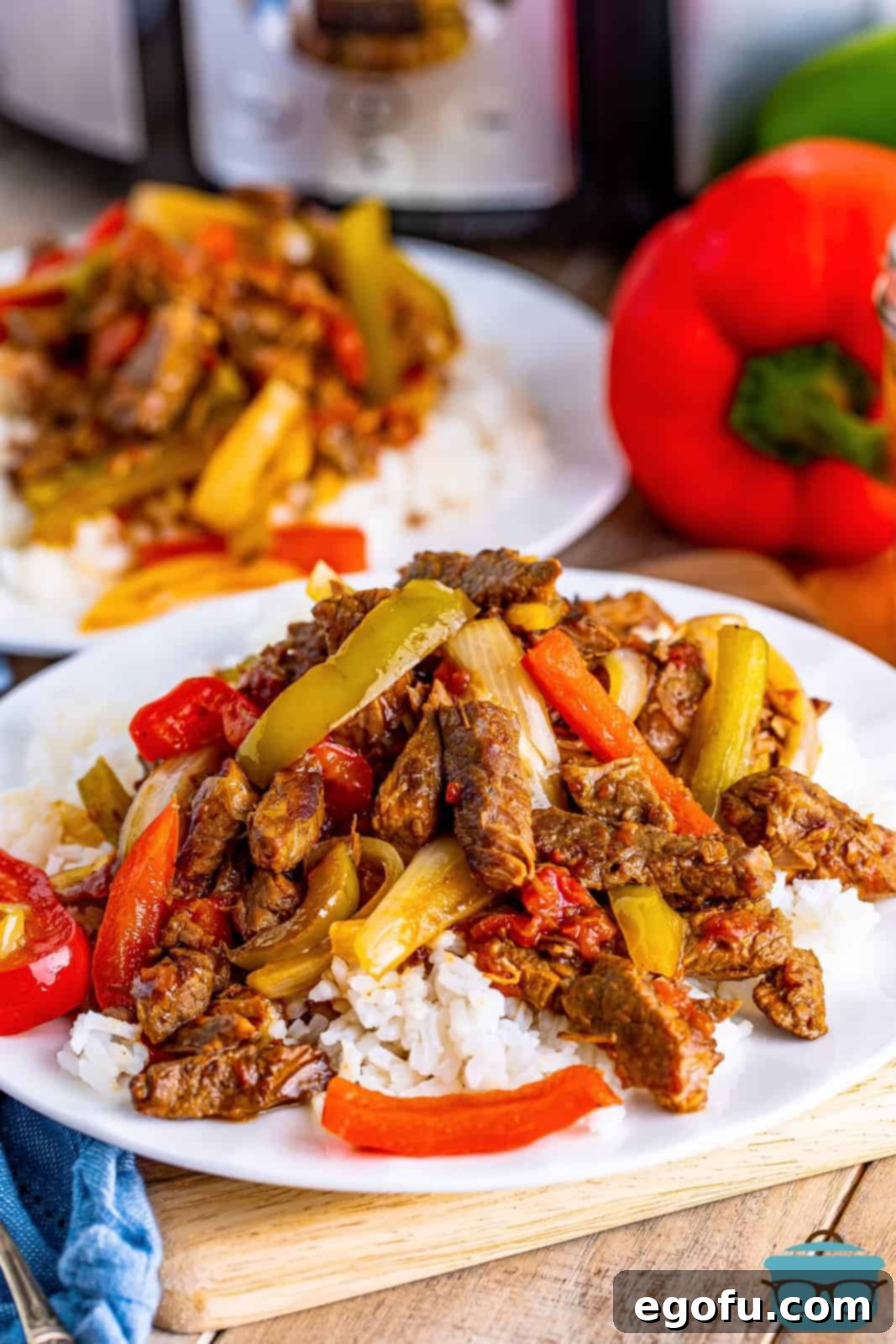 Slow Cooker Pepper Steak 2 Pepper steak served over white rice on a round white plate, showcasing the tender beef and vibrant peppers.