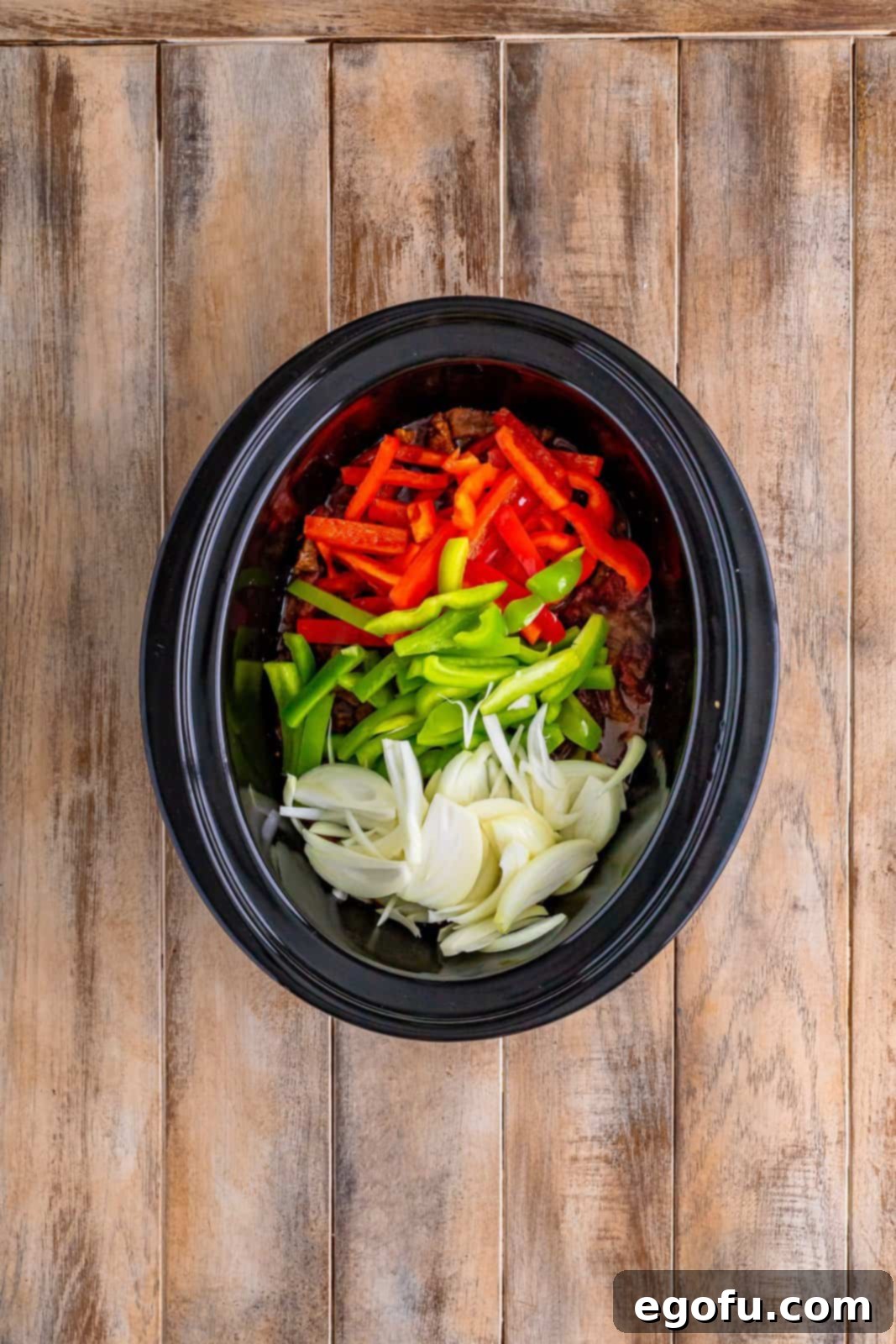 Slow Cooker Pepper Steak 11 Sliced red peppers, green peppers, and onion added to the partially cooked steak in the slow cooker during the final hour of cooking.