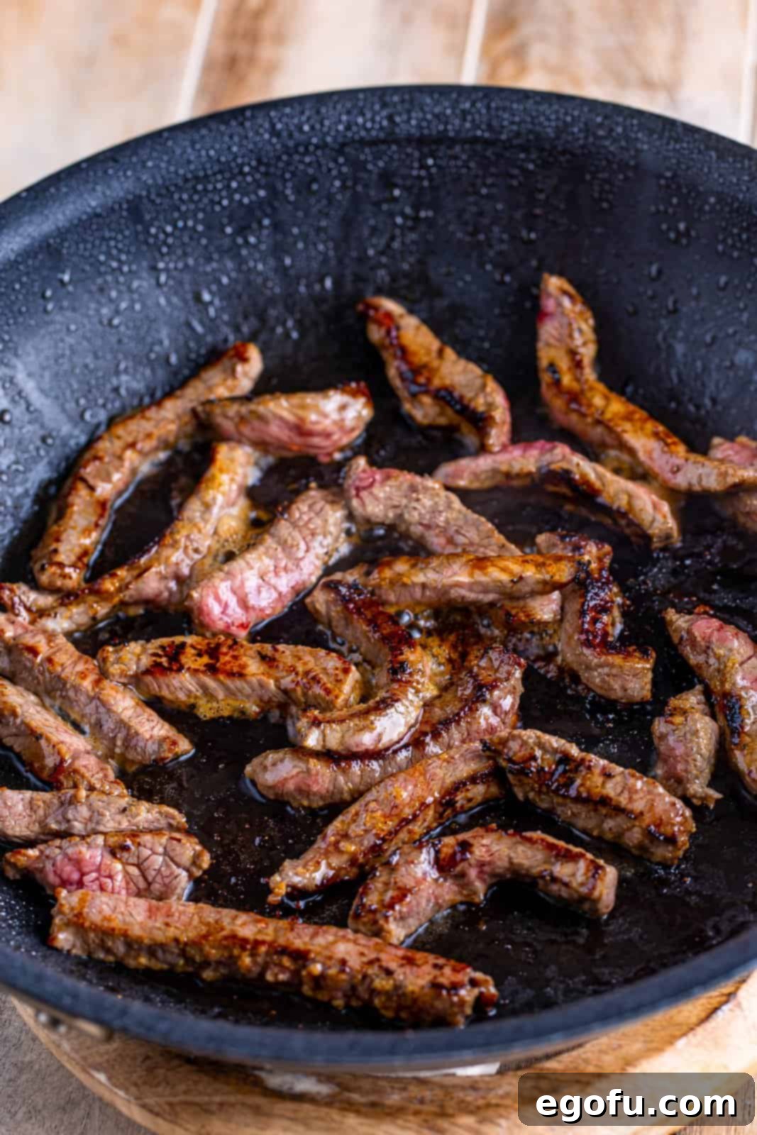 Slow Cooker Pepper Steak 6 Browned beef strips sizzling in a hot skillet, showing a beautiful sear.