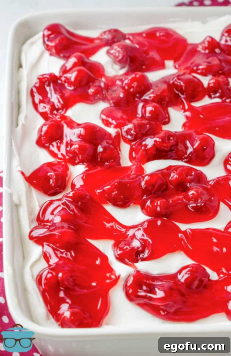 Ruby Snowdrift Cake 11 A can of glossy cherry pie filling swirled invitingly on top of the finished poke cake, with the white whipped topping visible underneath.