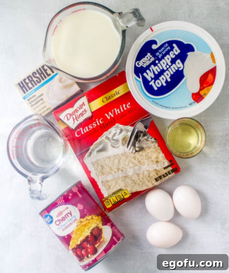 Ruby Snowdrift Cake 4 A display of essential ingredients for the Cherries in the Snow Poke Cake: Duncan Hines White Cake Mix, Cool Whip whipped topping, cherry pie filling, egg whites, Hershey's White Chocolate Pudding, and milk, all ready for preparation.
