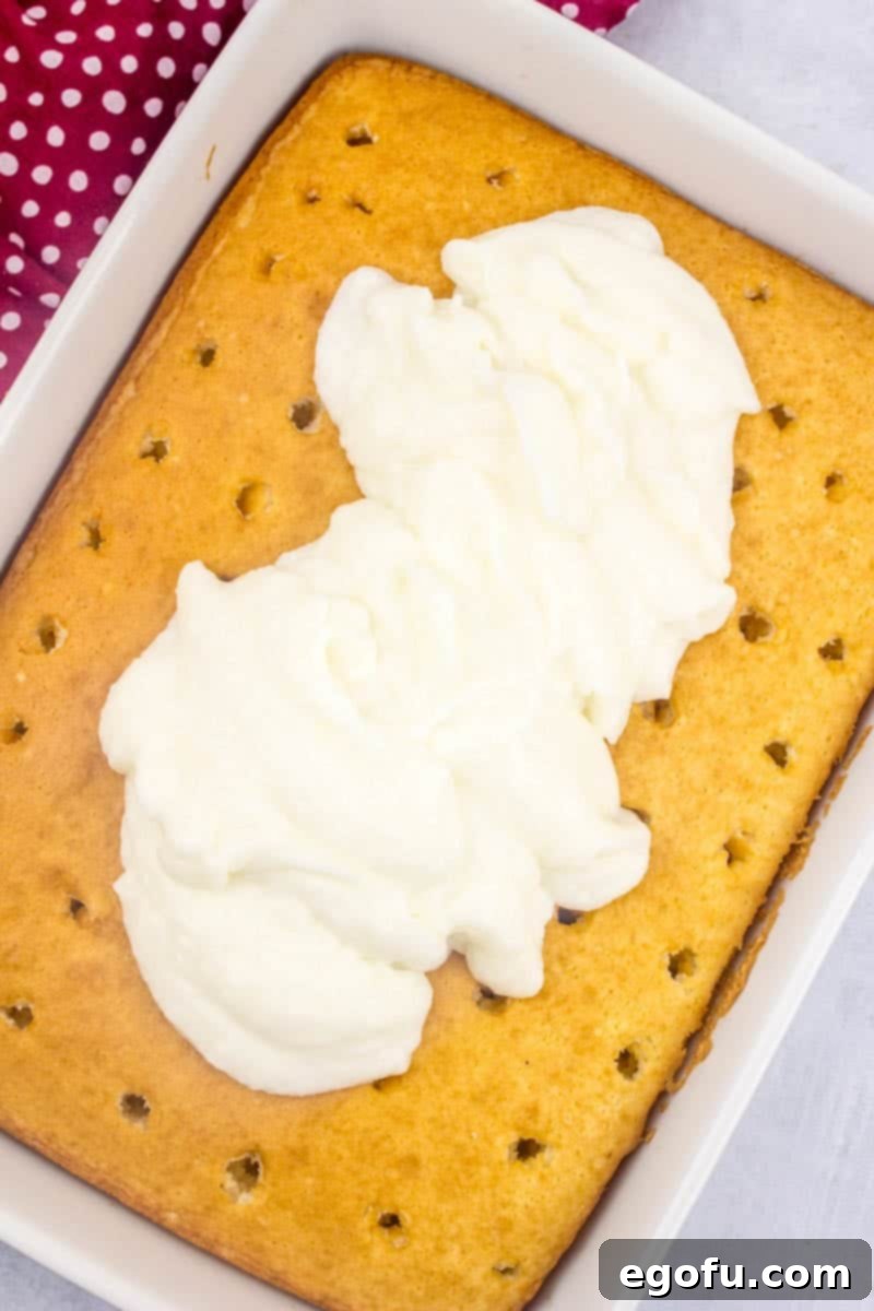 Ruby Snowdrift Cake 8 Prepared white chocolate pudding being spread over the poked cake, demonstrating how it fills the holes and covers the surface.