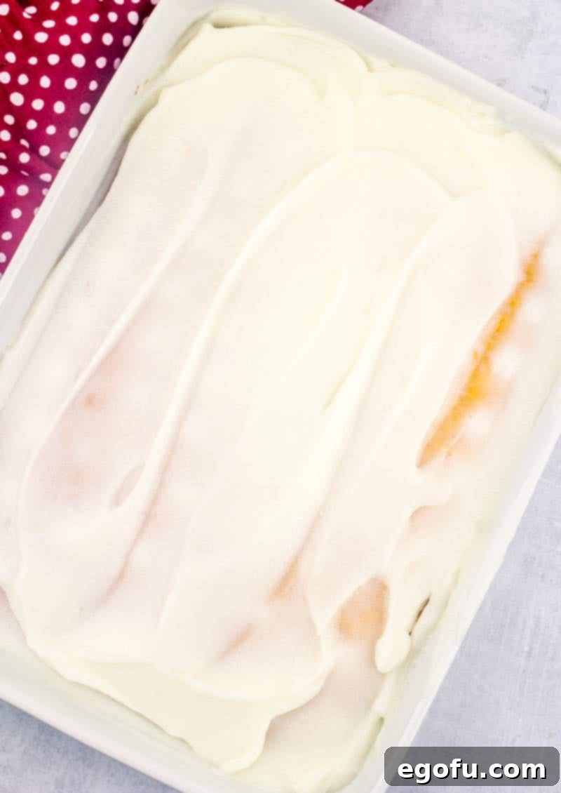 Ruby Snowdrift Cake 9 A rectangular baking dish with the cake fully covered in an even layer of white chocolate pudding, cooling and setting.