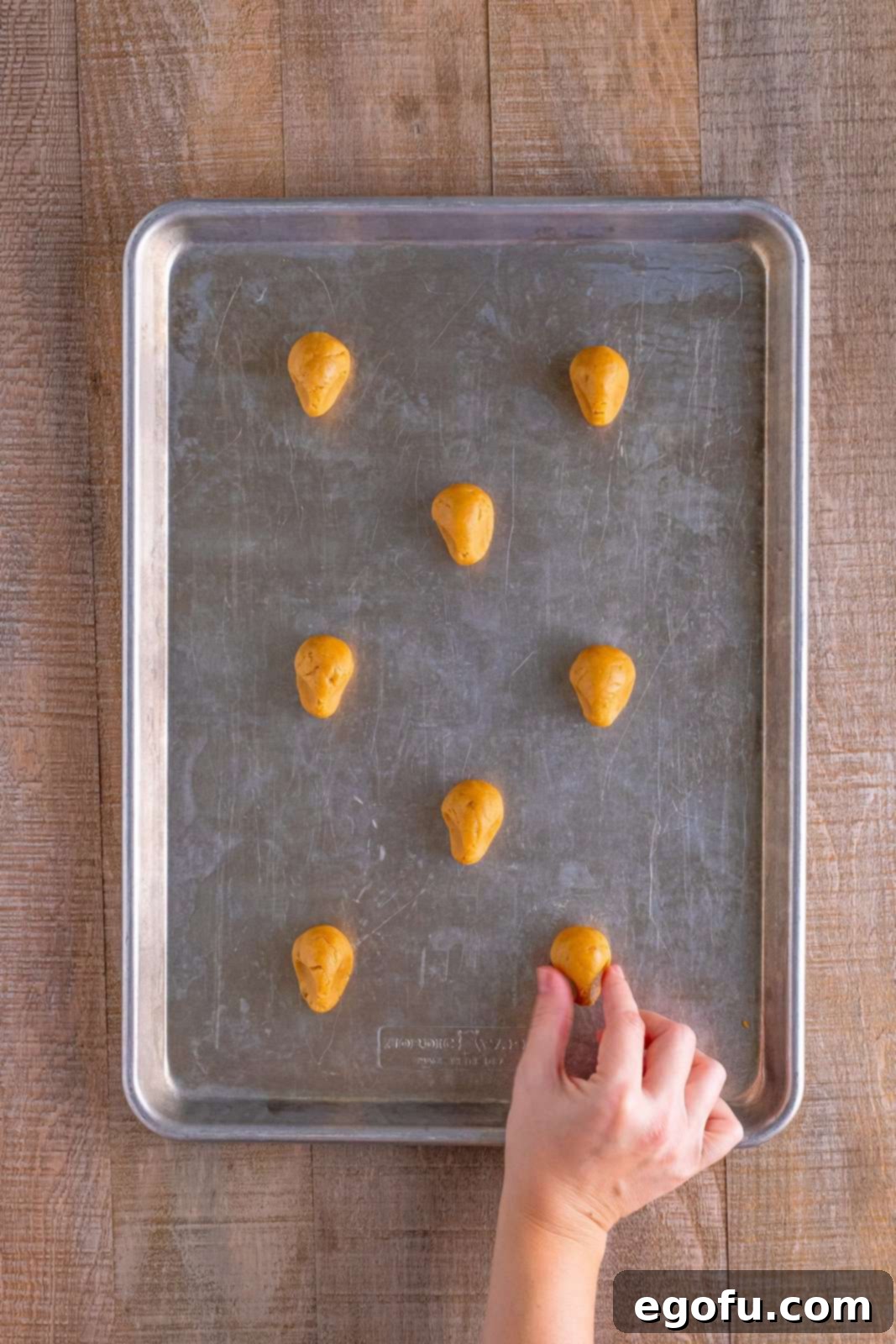 Red Nosed Reindeer Treats 10 a hand pinching the bottom of the rolls of cookie dough to make a reindeer face shape.