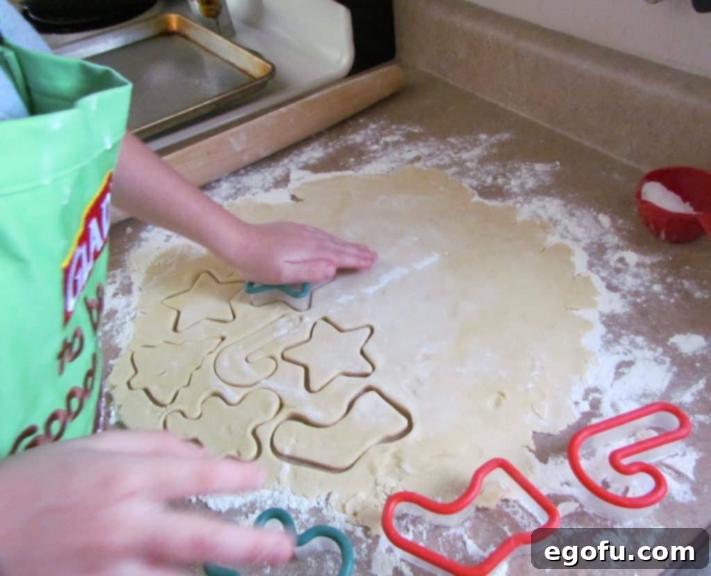 a child pressing a cookie cutter into rolled out cookie dough