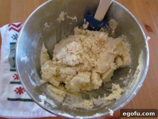 scraping the sides of the steel mixing bowl with a silicone spatula 