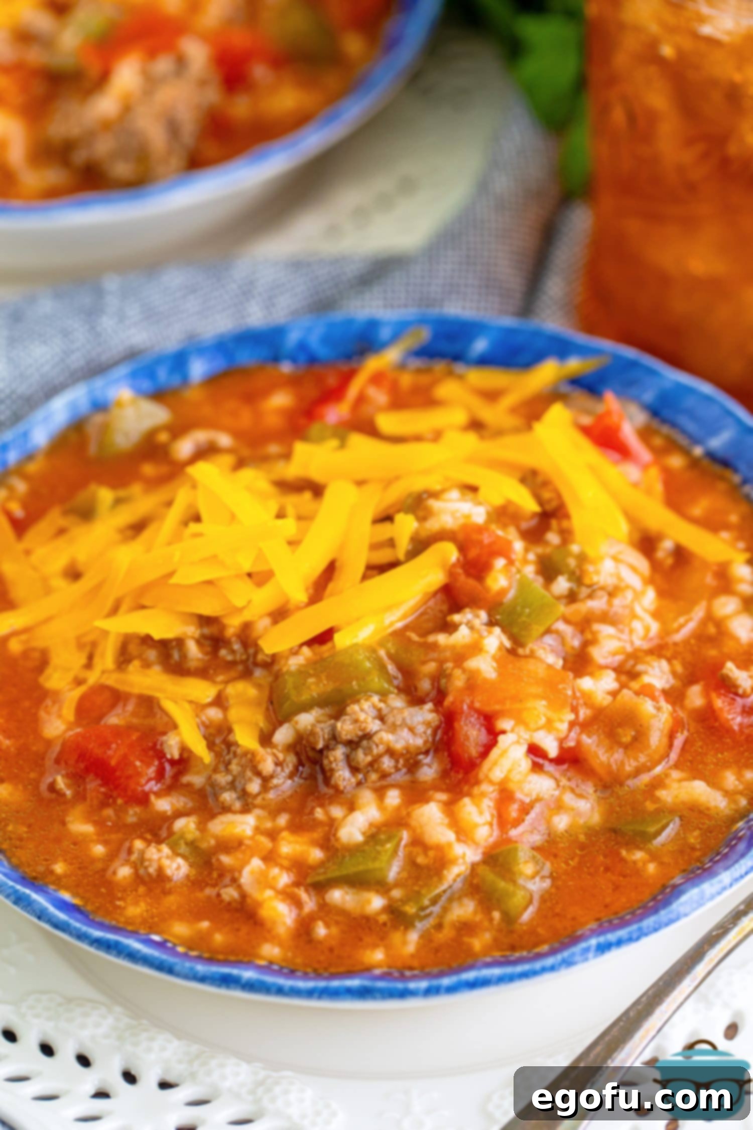 A bowl of Stuffed Pepper Soup with shredded cheese on top, ready to be enjoyed.