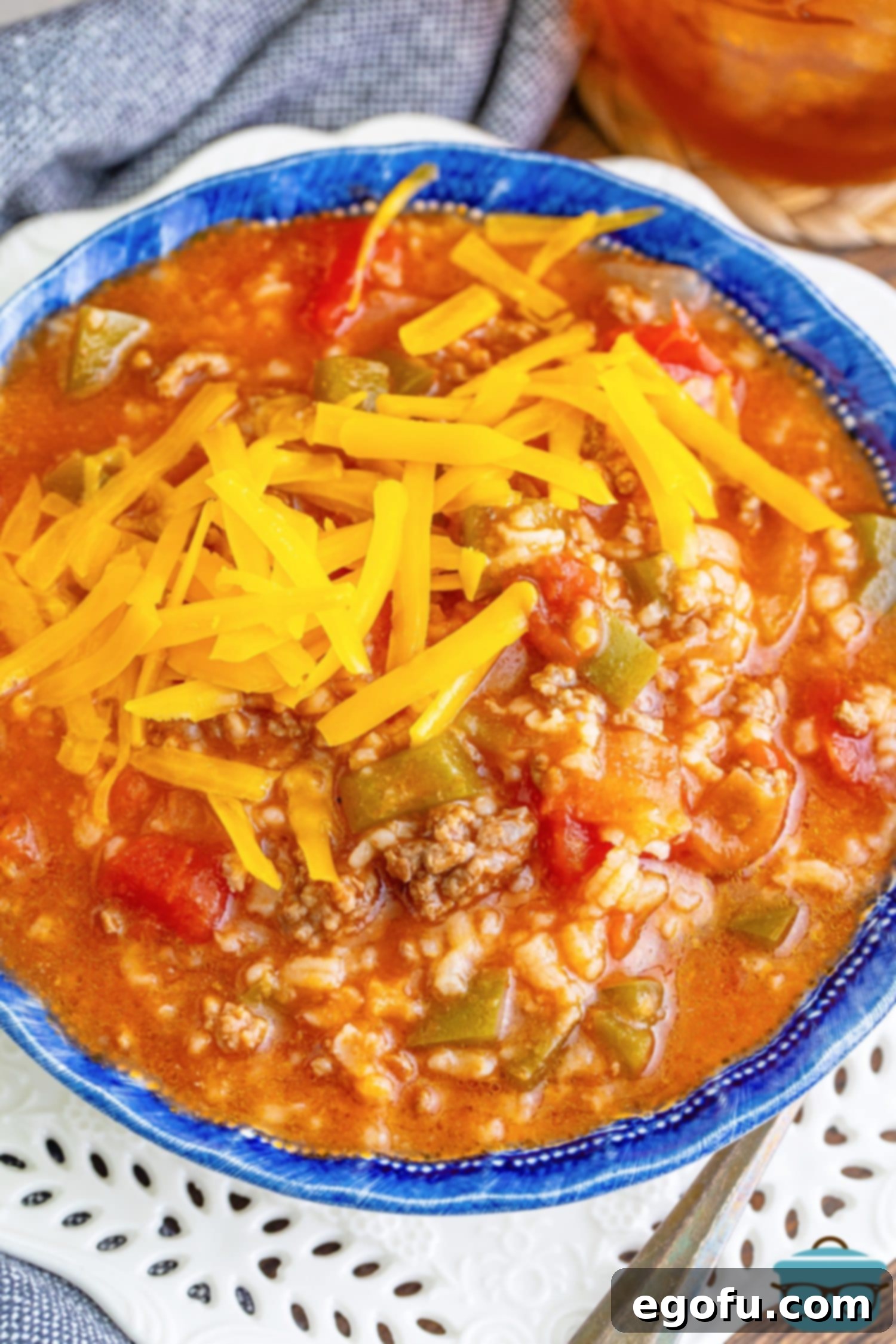 Looking down on a perfectly garnished bowl of Stuffed Pepper Soup, topped with melted shredded cheese.