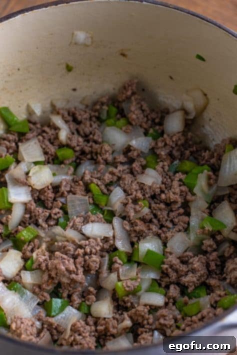 Ground beef, onion, and bell pepper cooking in a pot.