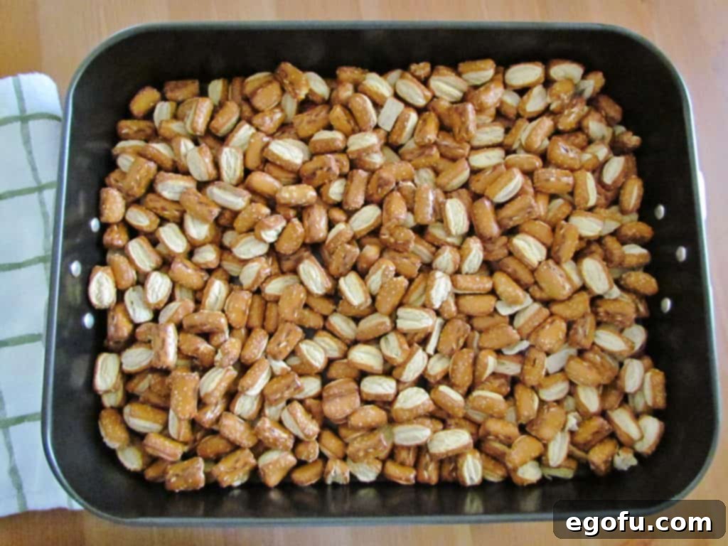 Pretzels spread out in a single layer in a large roasting pan, ready for seasoning.