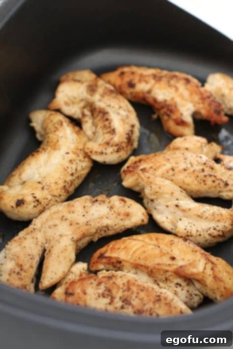 Browned chicken tenderloins placed in the bottom of a slow cooker insert.