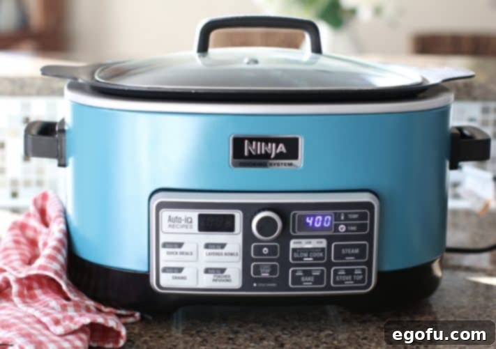 Covered turquoise slow cooker showing a 4-hour cooking time on a digital display.