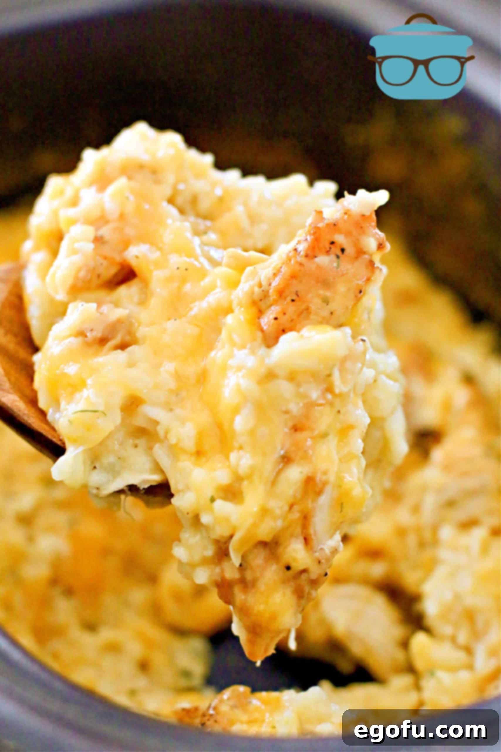 A wooden spoon holding a perfect serving of cheesy chicken and rice, ready to eat.
