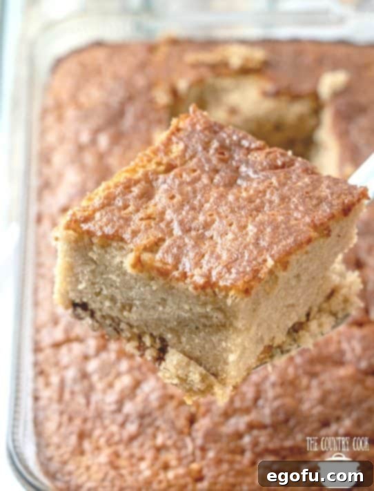 fully baked pecan praline cake with one slice being held up with a spatula.