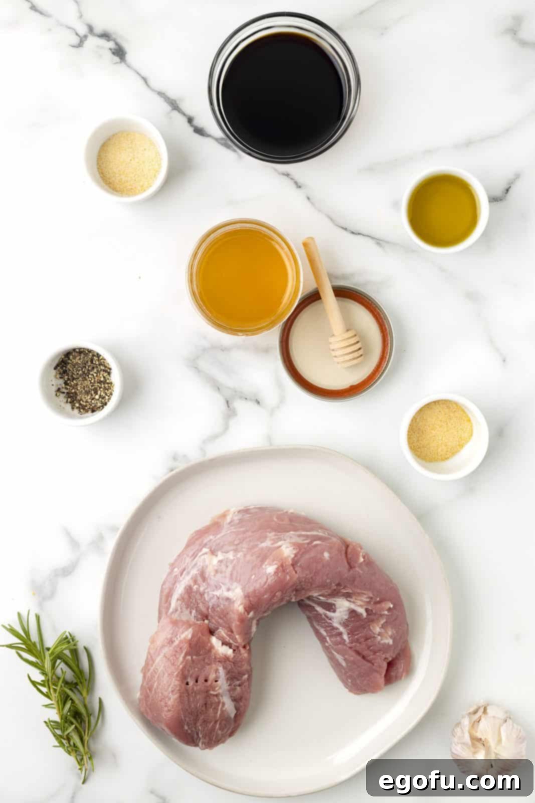 All the fresh ingredients laid out: pork tenderloin, soy sauce, olive oil, honey, minced garlic, fresh rosemary, garlic powder, onion powder, and black pepper.