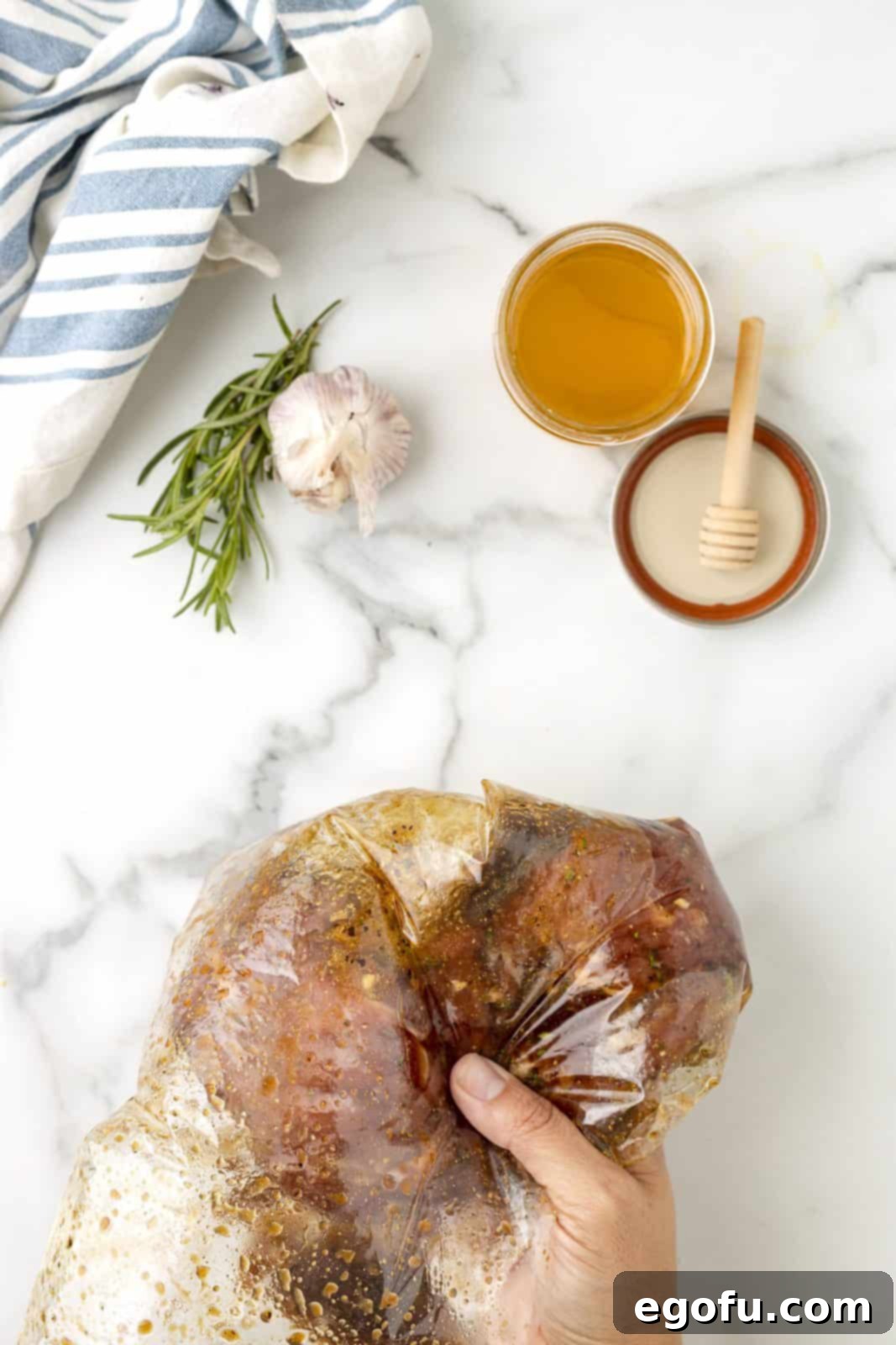 A hand gently massaging the marinade into the pork tenderloin inside a sealed bag.