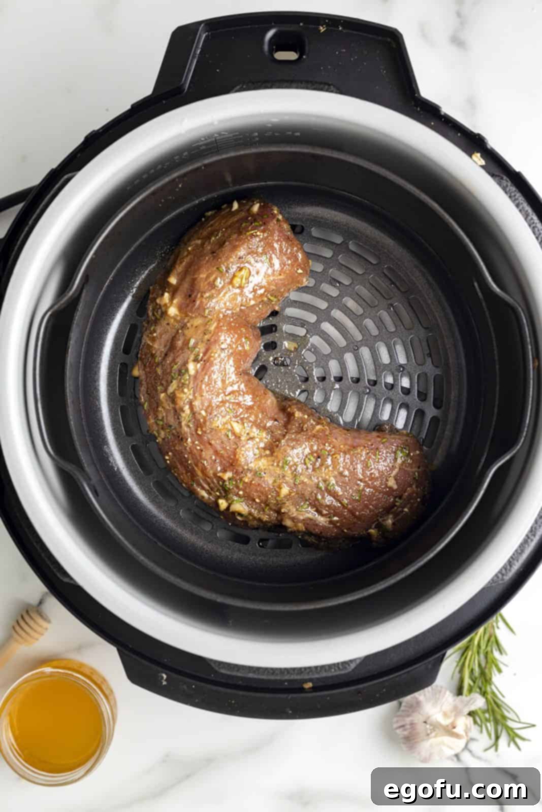 The marinated pork tenderloin being carefully placed into the air fryer basket.