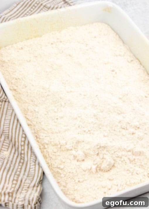 Dry spice cake mix sprinkled over top of pumpkin pie mix in a baking dish.