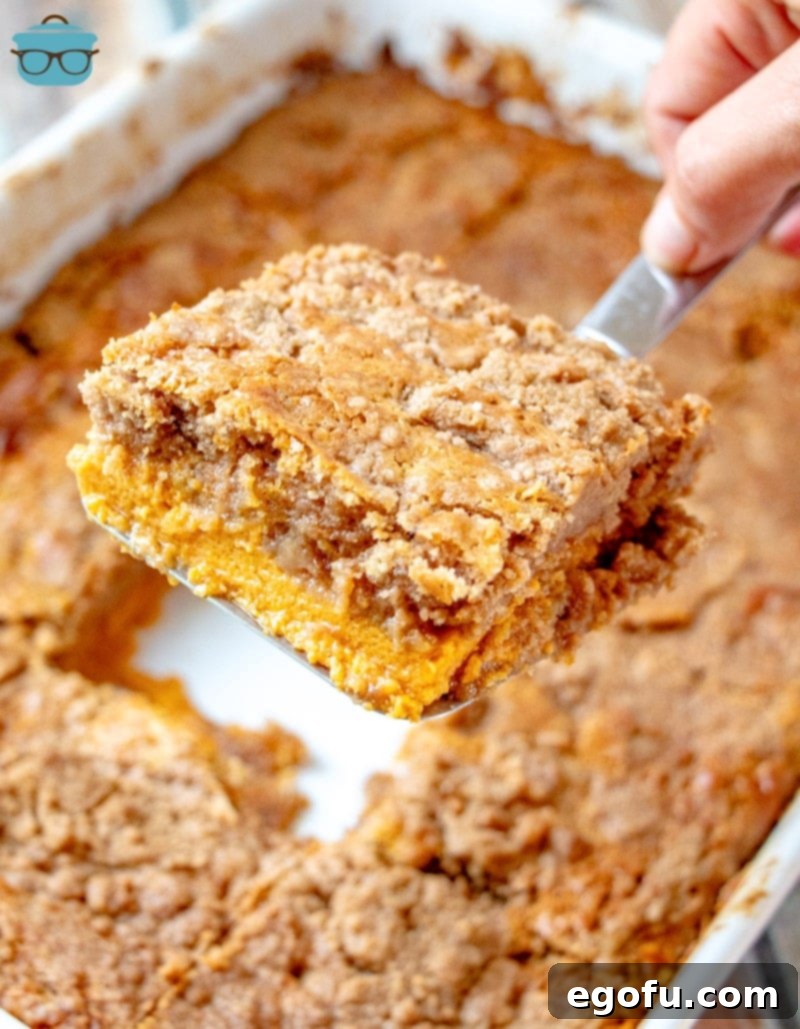 A spatula lifting a perfect slice of Pumpkin Dump Cake from the baking dish, revealing the rich layers.