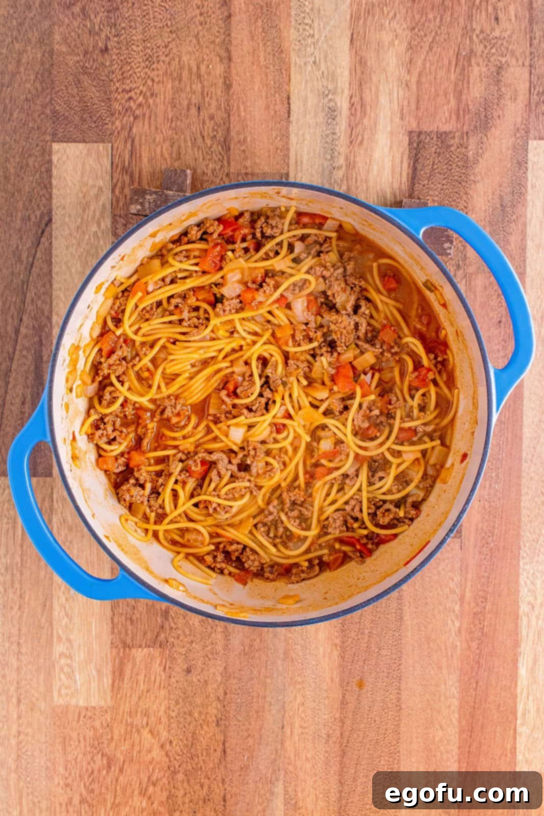 Perfectly cooked spaghetti, swimming in a rich, savory taco-seasoned sauce within the Dutch oven, steam gently rising.