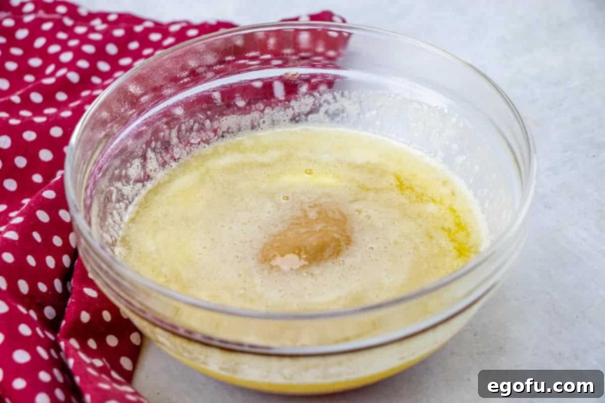 Melted butter, peanut butter, and honey in a clear glass bowl, smooth and ready to be mixed.