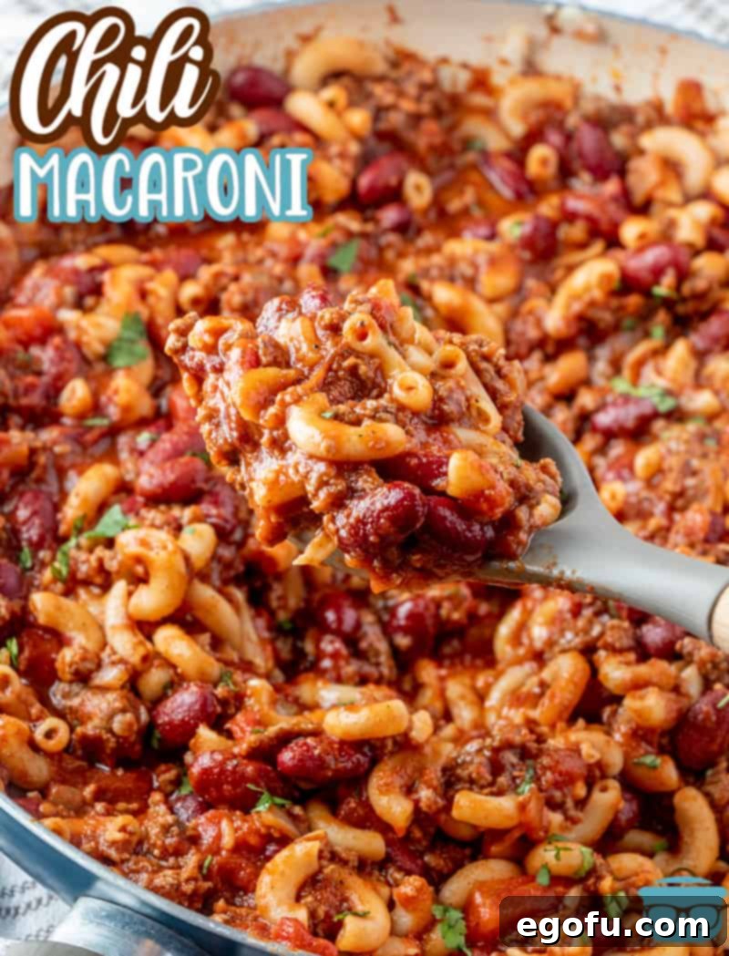 fully cooked chili Mac in a large skillet with a large cooking spoon scooping some out of the pan, showcasing its rich texture.