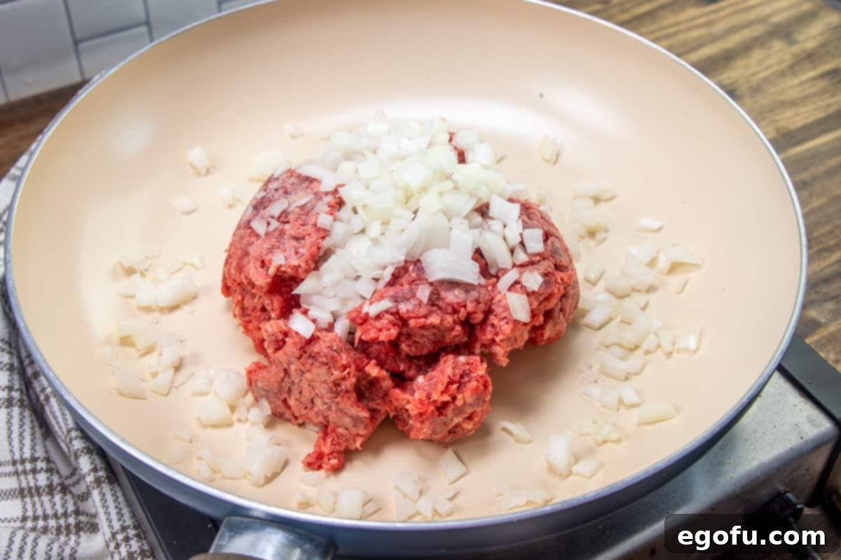 ground beef and diced onion in a large pan, sautéing together.