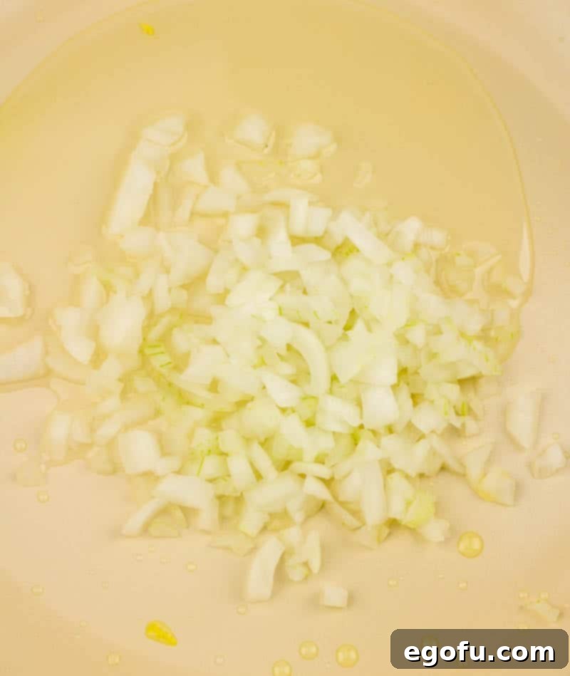 Vibrant Veggie Fried Rice 8 Diced onions being sautéed in a skillet with a small amount of oil, turning translucent as they cook, for the fried rice base.