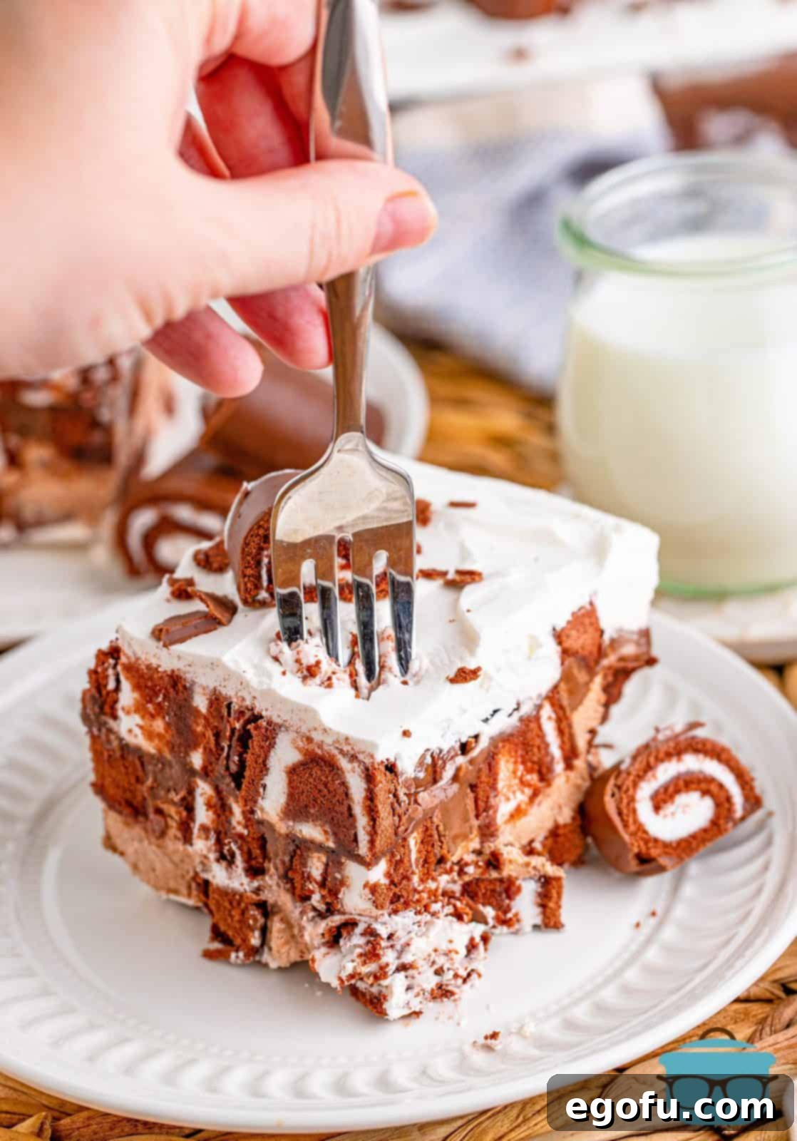 Easy No-Bake Swiss Roll 2 Fork going into slice of No-Bake Swiss Roll Cake on white plate.