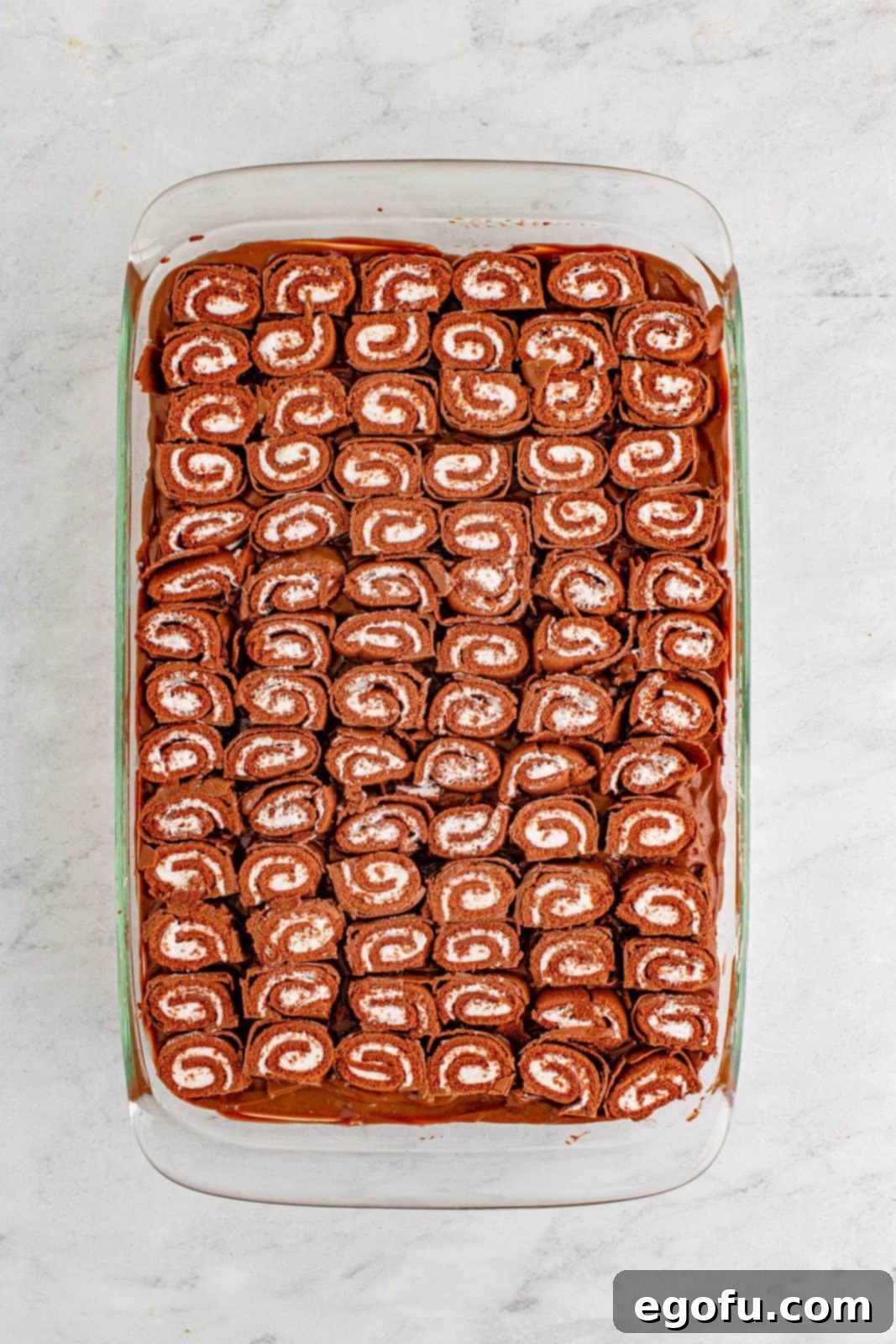 Easy No-Bake Swiss Roll 12 Cut swiss cake rolls placed on top of the chocolate pudding.