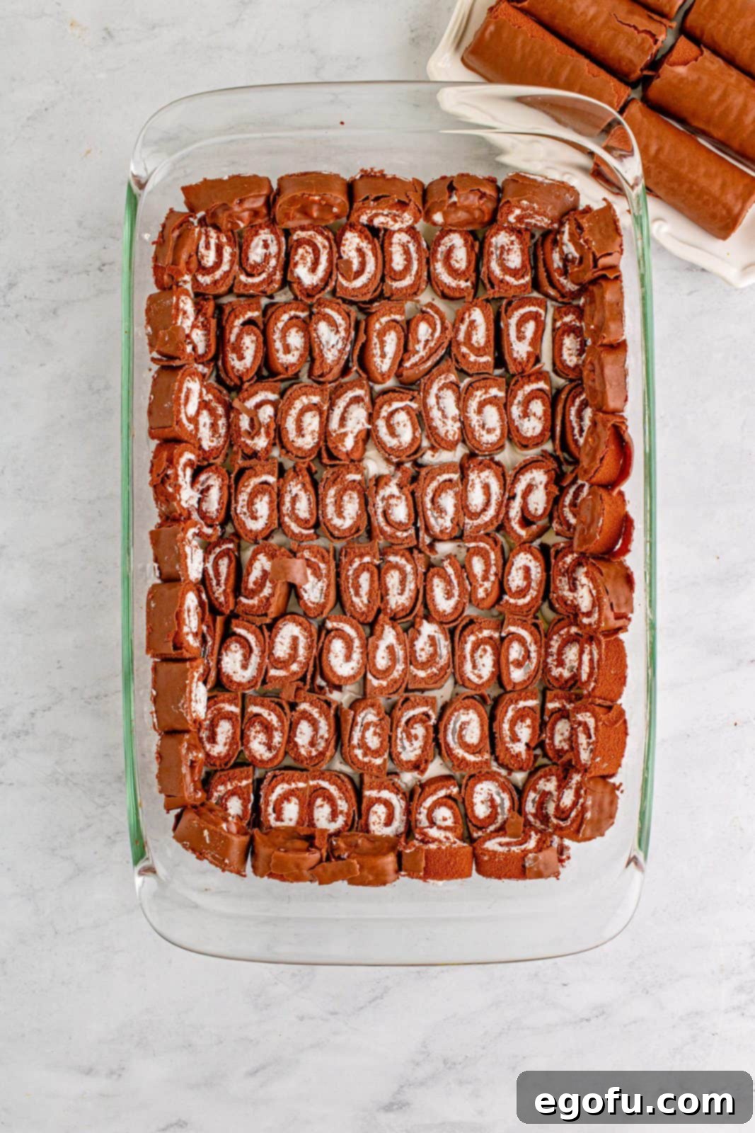 Easy No-Bake Swiss Roll 7 Cut swiss cake rolls placed on bottom and up sides of baking pan.