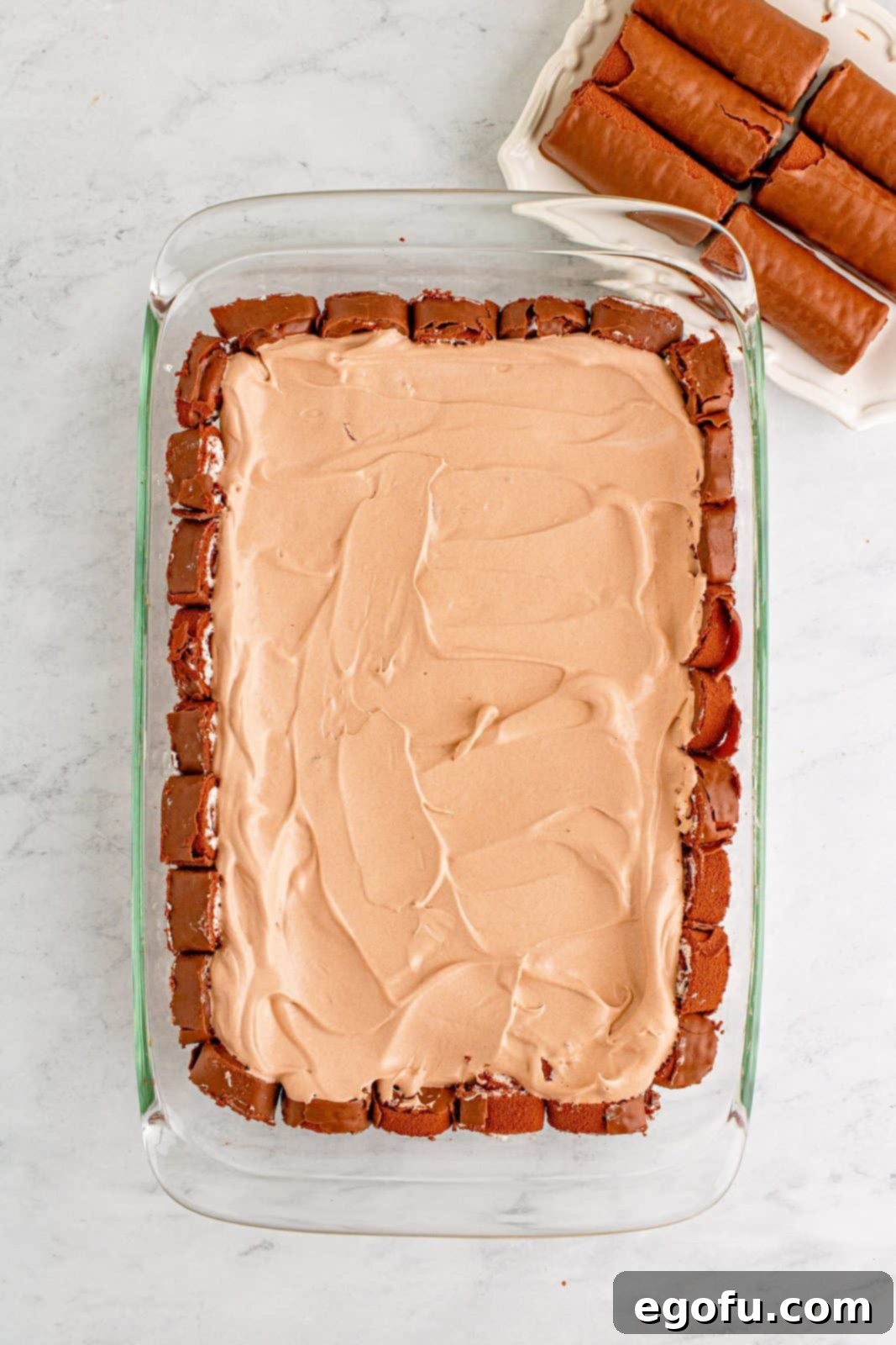 Easy No-Bake Swiss Roll 9 Cool whip and pudding mixture spread over swiss cake rolls in baking dish.