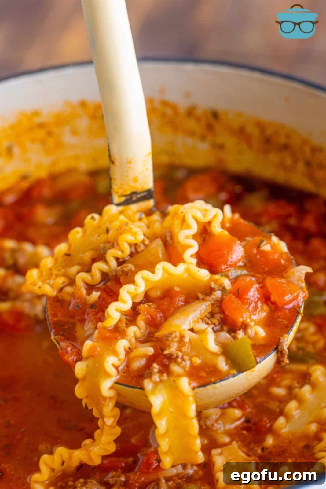 A ladle serving a generous portion of steaming Lasagna Soup from a large pot, showcasing the rich broth, pasta, and cheese.
