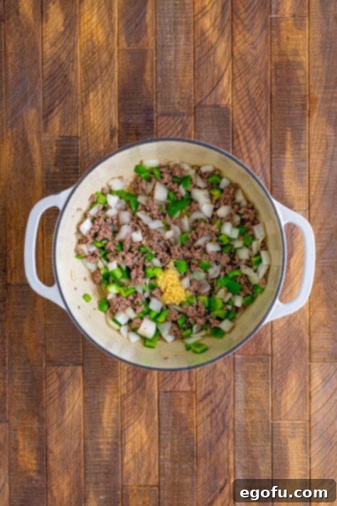 Minced garlic added to cooked ground beef in pot.