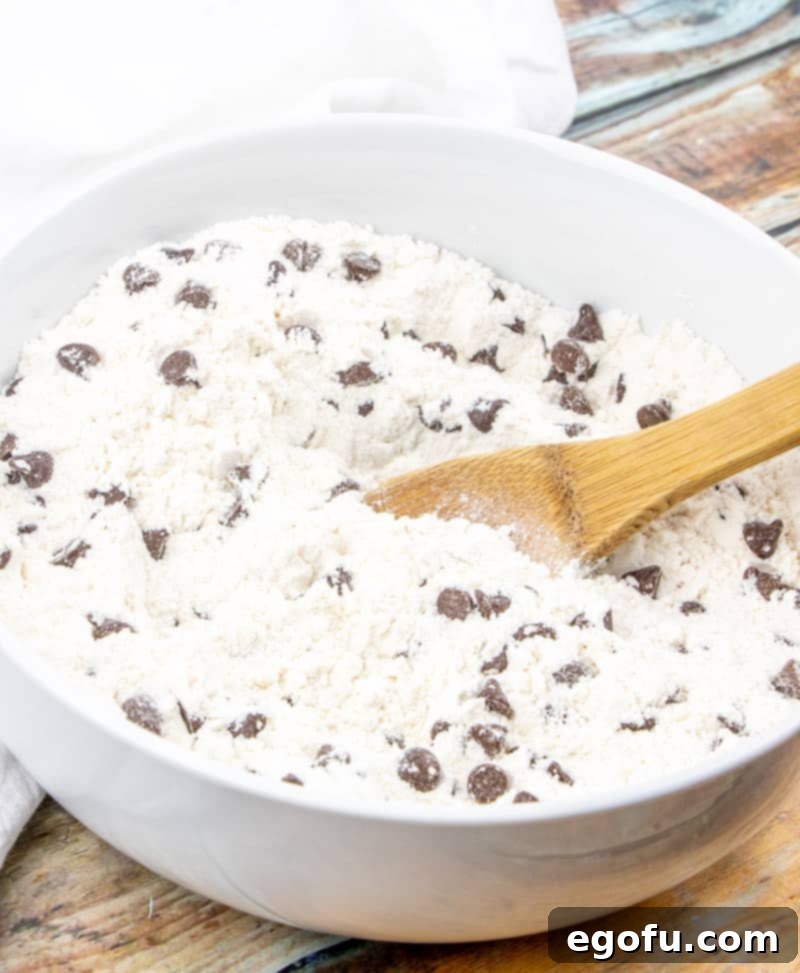 Decadent Milk Chocolate Chip Muffins 5 milk chocolate chips added to all purpose flour, sugar, baking powder and salt in a bowl.