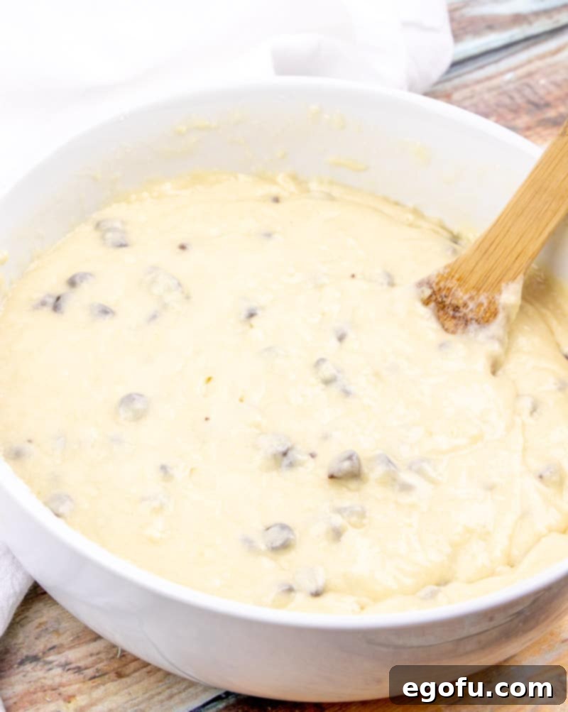 Decadent Milk Chocolate Chip Muffins 7 stirring wet batter ingredients with dry batter ingredients in a bowl.