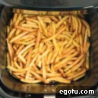 Square image of finished french fries in air fryer.