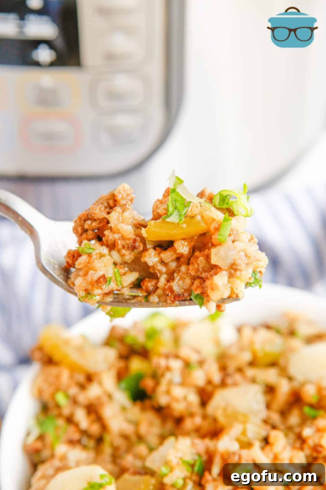 A fork lifting a generous portion of Instant Pot Dirty Rice, perfectly cooked and garnished with fresh green onions and parsley, ready to be enjoyed.