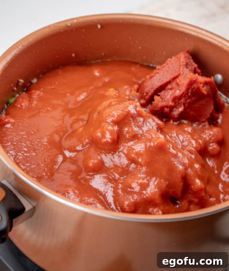 tomato sauce, diced tomatoes added into cooked ground beef mixture in large pot.