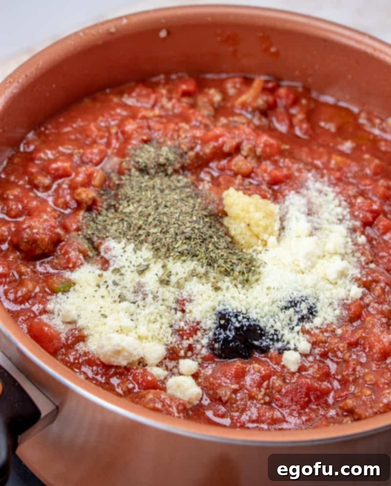 Parmesan cheese, oregano, garlic, grape jelly added to spaghetti sauce mixture.
